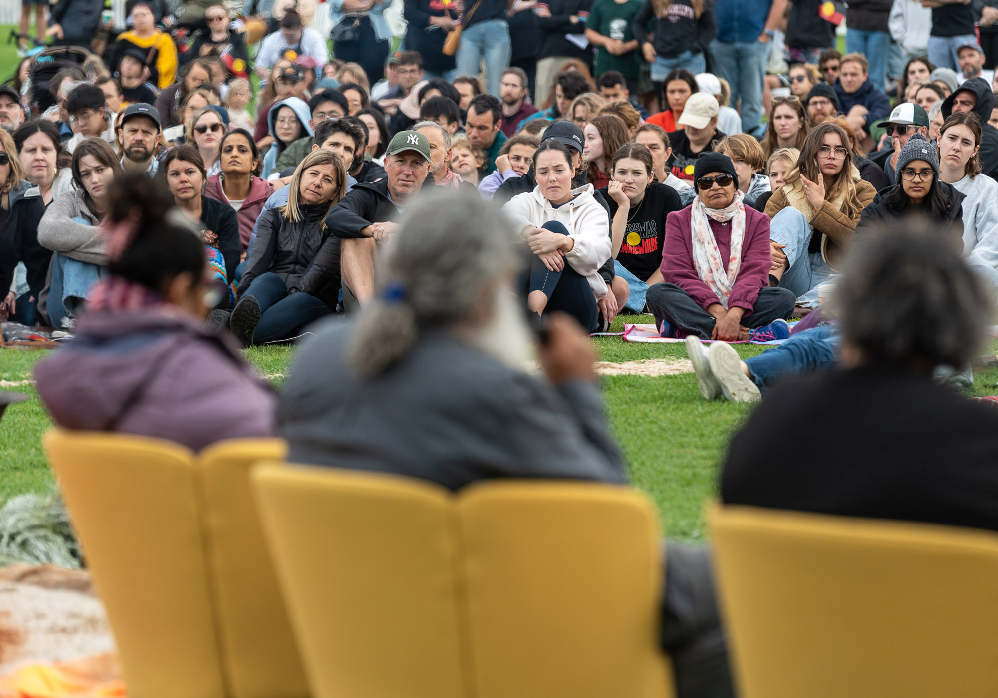 Attendees watch First Nations Elders having a yarn by the fire during the Mourning in the Morning event